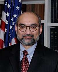 Headshot of Jagadeesh Gokhale, bespectacled man with beard in a suit and tie